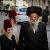 man with shtreimel in street on purim next to two young boys with fez hats