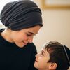 mother in a black shirt looking down smilingly at her young son