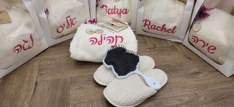 clear gift bags containing six white towels with pink names embroidered on them 